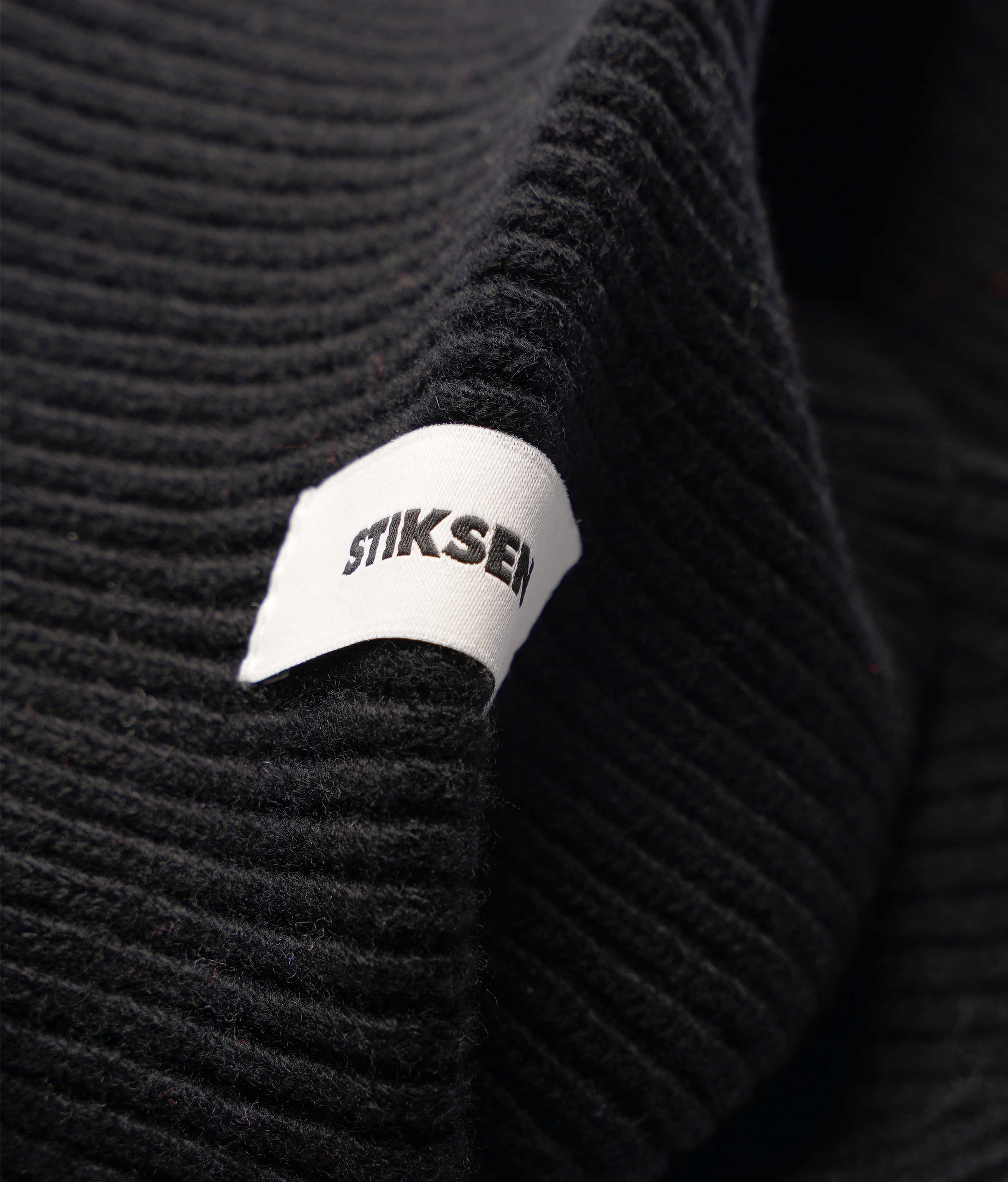 Close-up of Stiksen woven logo label on Black Beanie 01 merino wool beanie