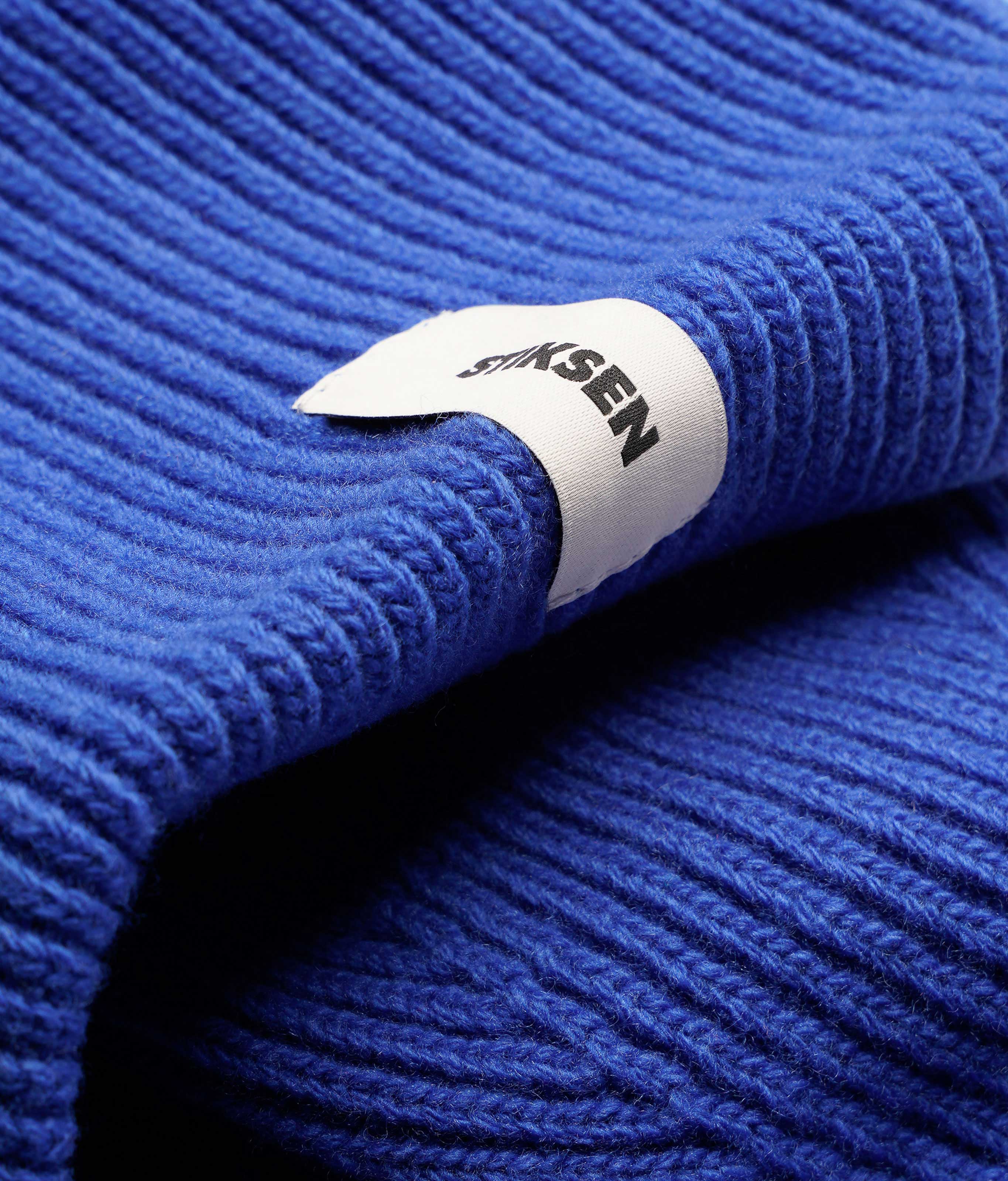 Close-up of Stiksen woven logo label on Cobalt Beanie 01 merino wool beanie