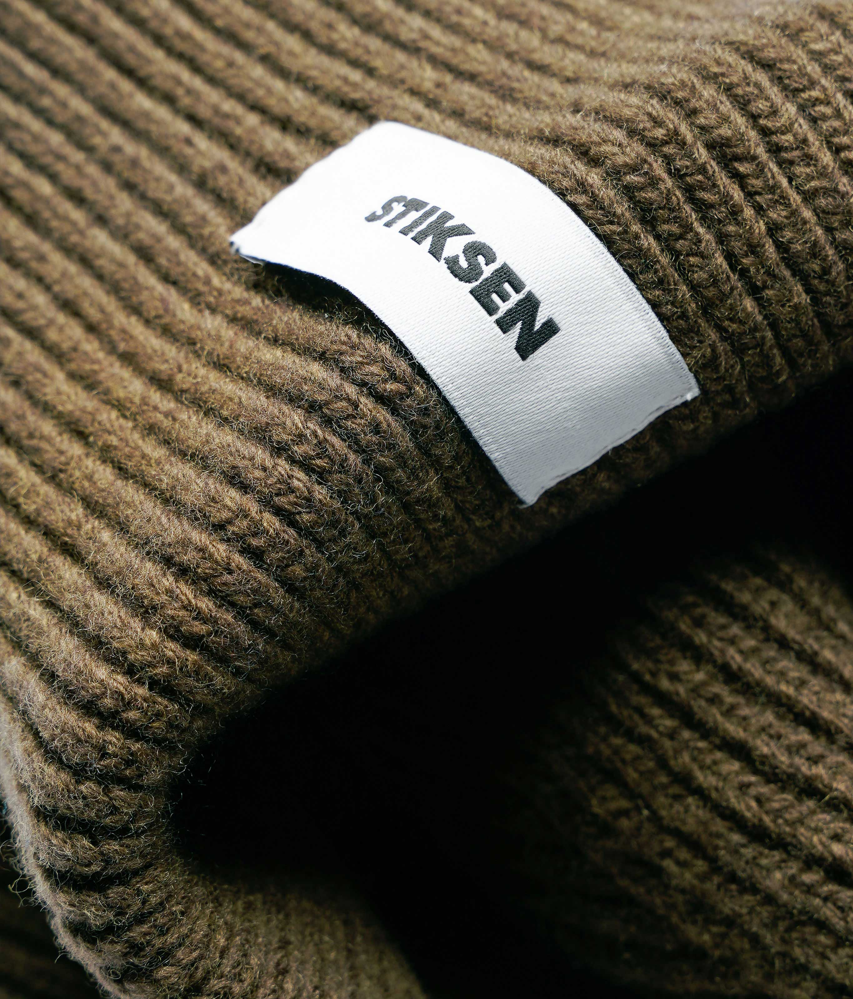 Close-up of Stiksen woven logo label on Ivy Beanie 01 merino wool beanie