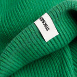 Close-up of Stiksen woven logo label on Kelly Green Beanie 01 merino wool beanie