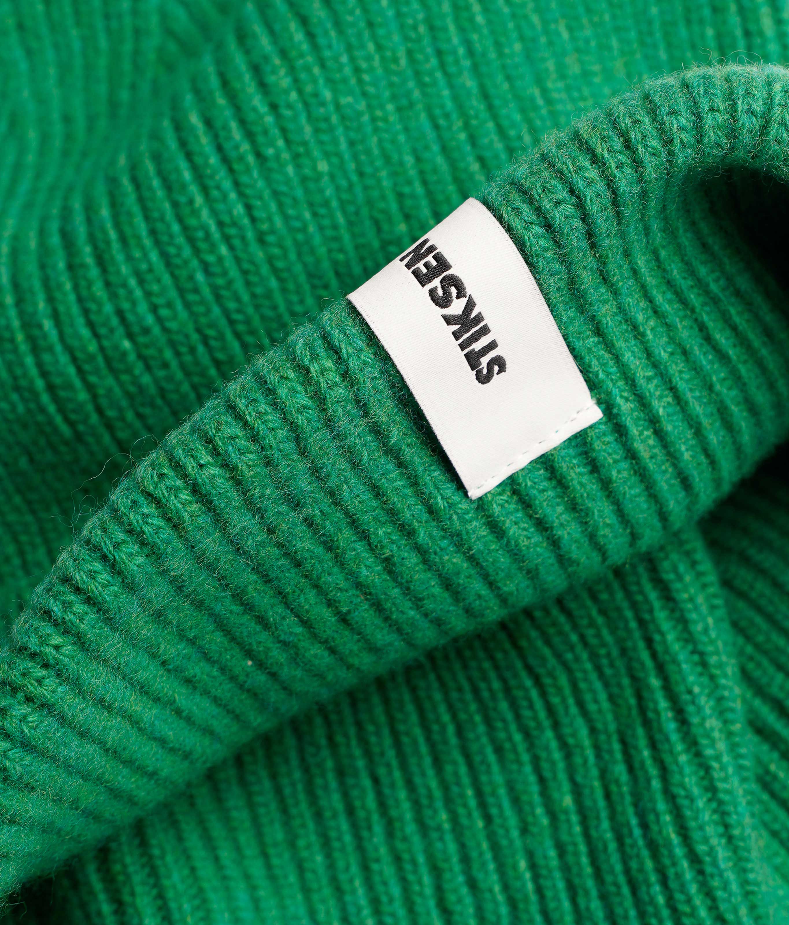 Close-up of Stiksen woven logo label on Kelly Green Beanie 01 merino wool beanie
