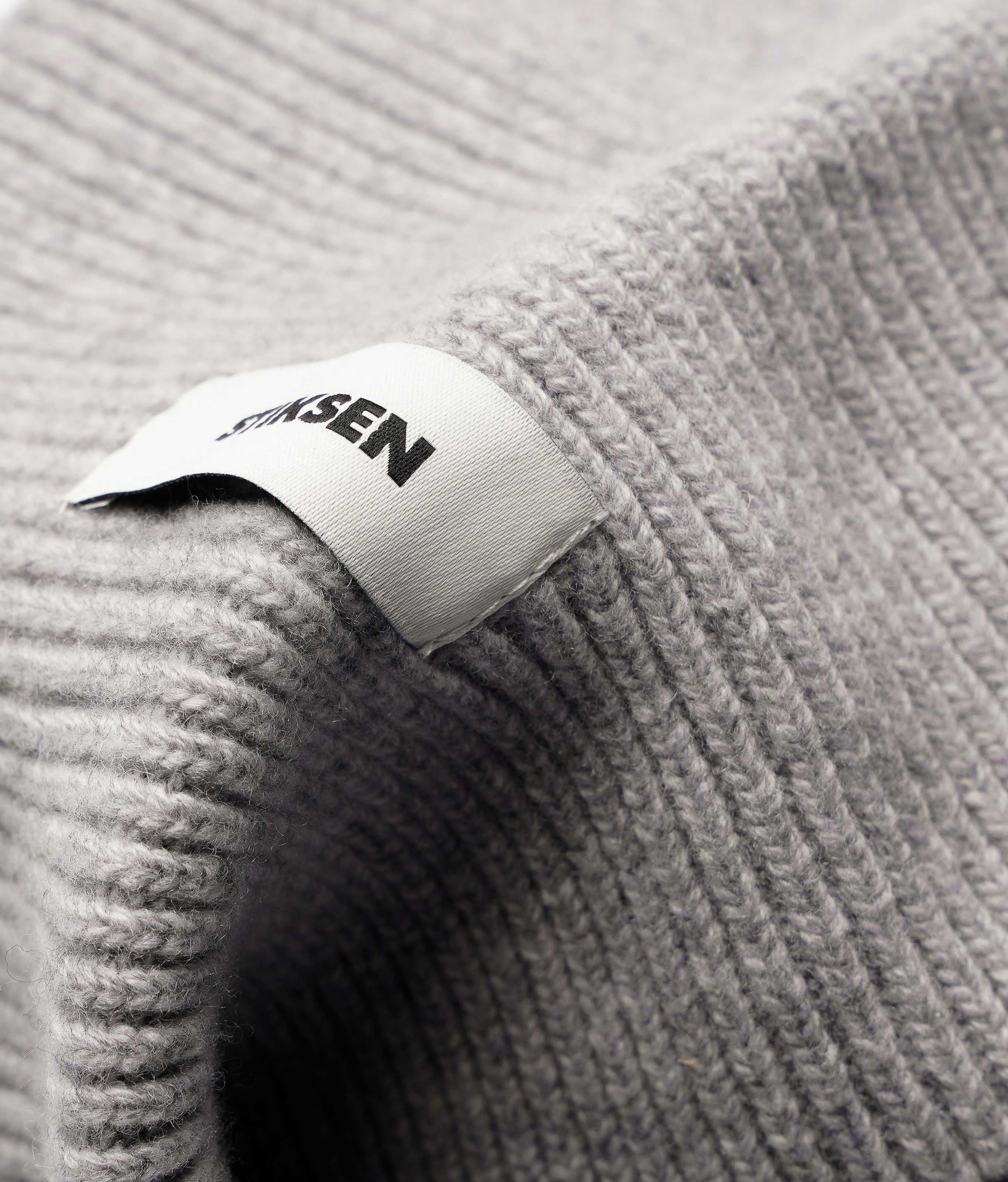 Close-up of Stiksen woven logo label on Light Grey Beanie 01 merino wool beanie