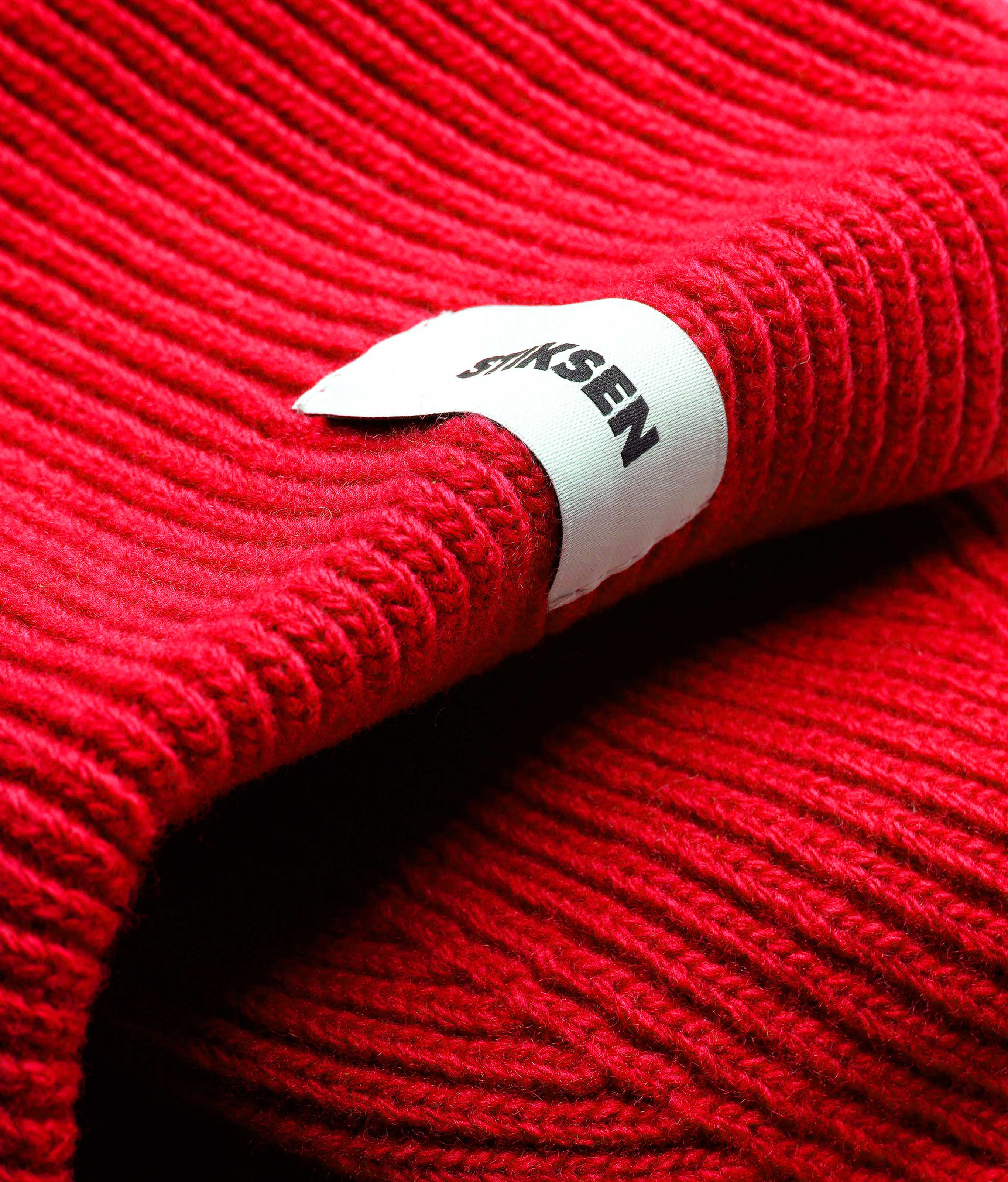 Close-up of Stiksen woven logo label on Red Beanie 01 merino wool beanie