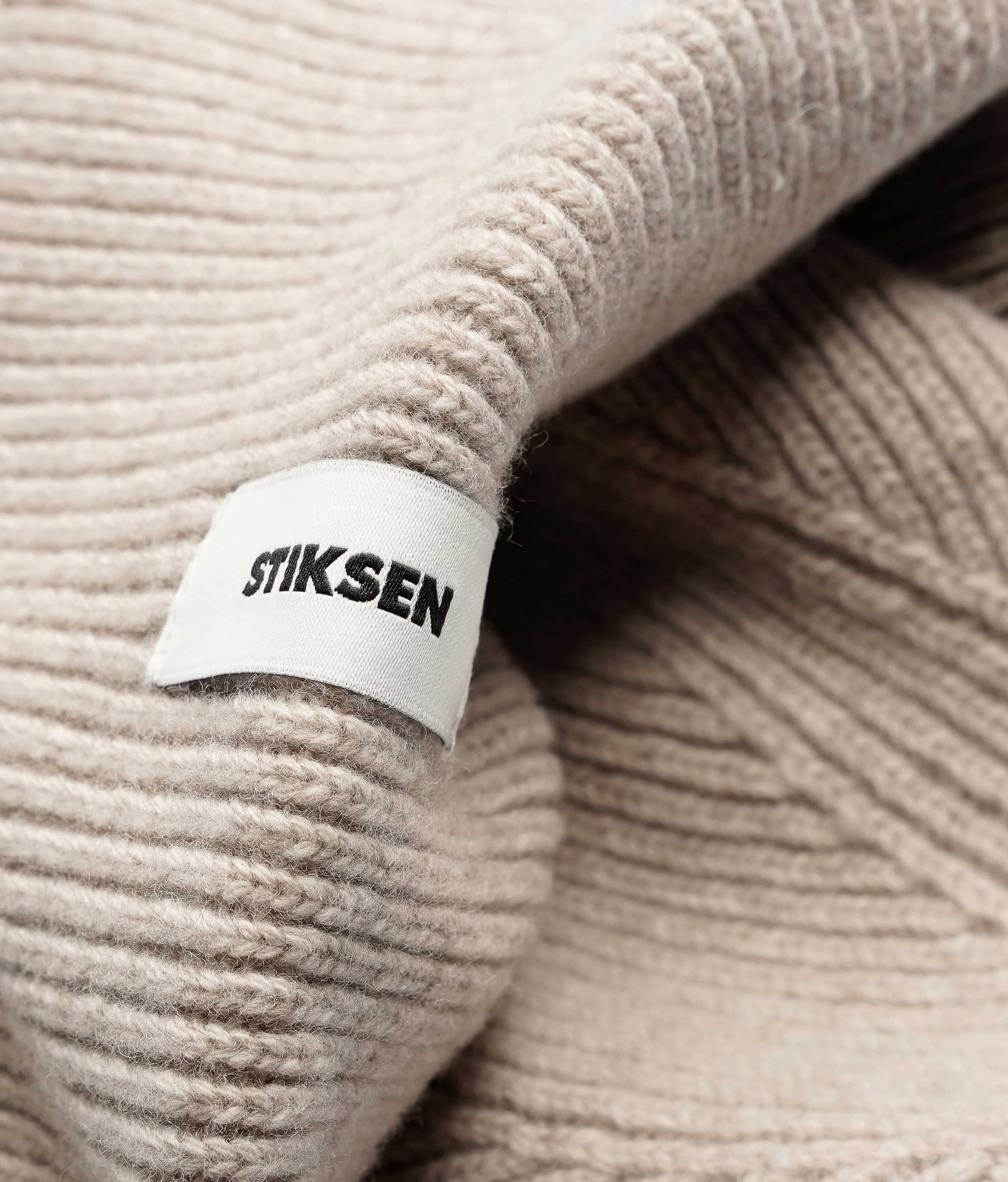 Close-up of Stiksen woven logo label on Sand Beanie 01 merino wool beanie
