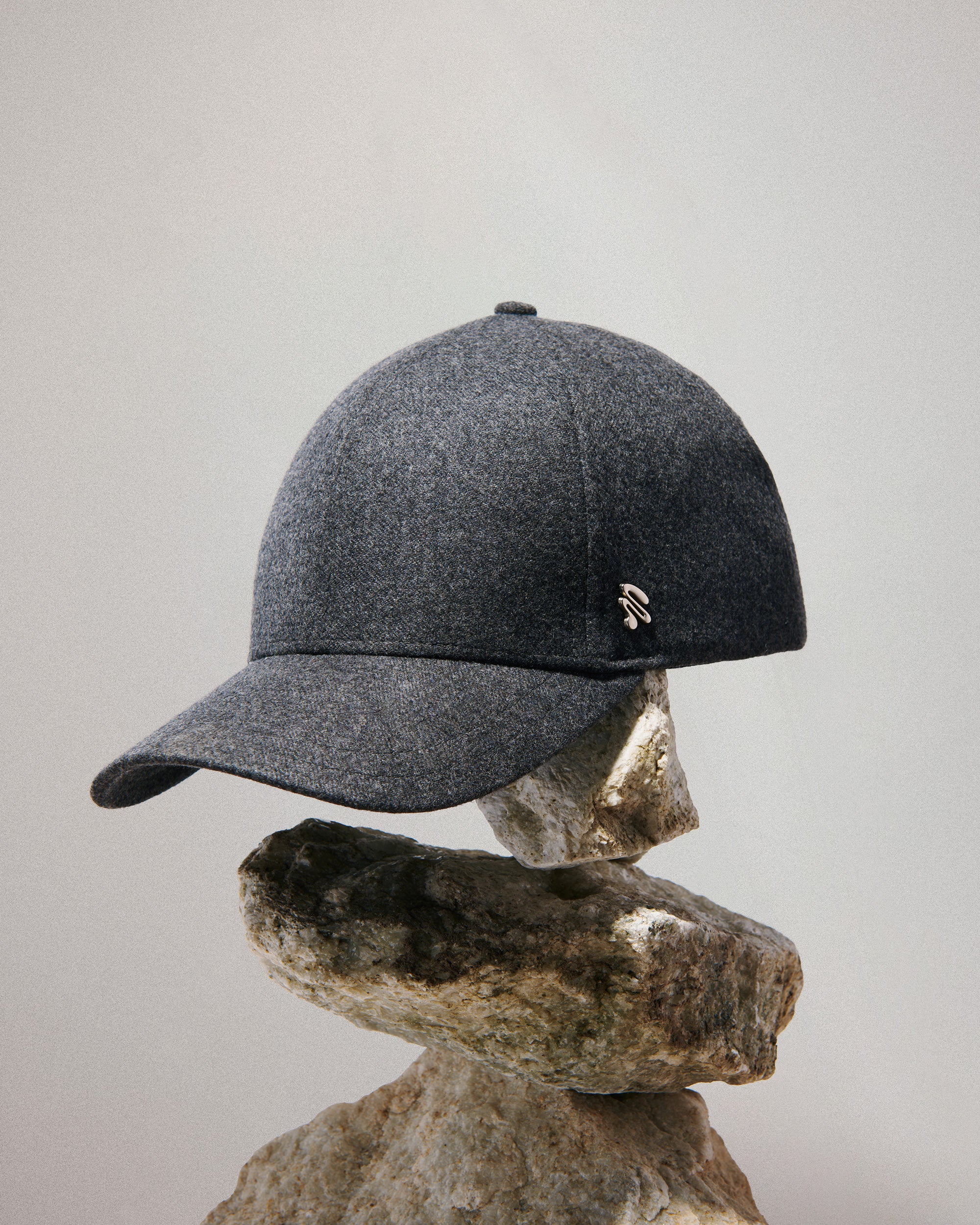 Elegant, minimalistic, grey baseball cap on a stone with a neutral background