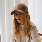 Stiksen 107 Linen Brown baseball cap worn by female model indoors in soft ambient lighting